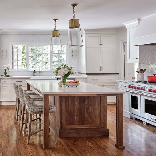 Bright white kitchen remodel in Charlotte, NC with a walnut island, Sereno Gold quartz countertops, brass and glass pendant lighting, white shaker cabinetry, Wolf dual-fuel range, and warm hardwood floors.