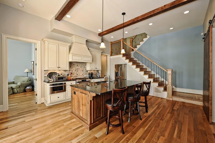 kitchen with brown hardwood floord and a wooden brown island near stairs going up by Hopedale Builders in Charlotte