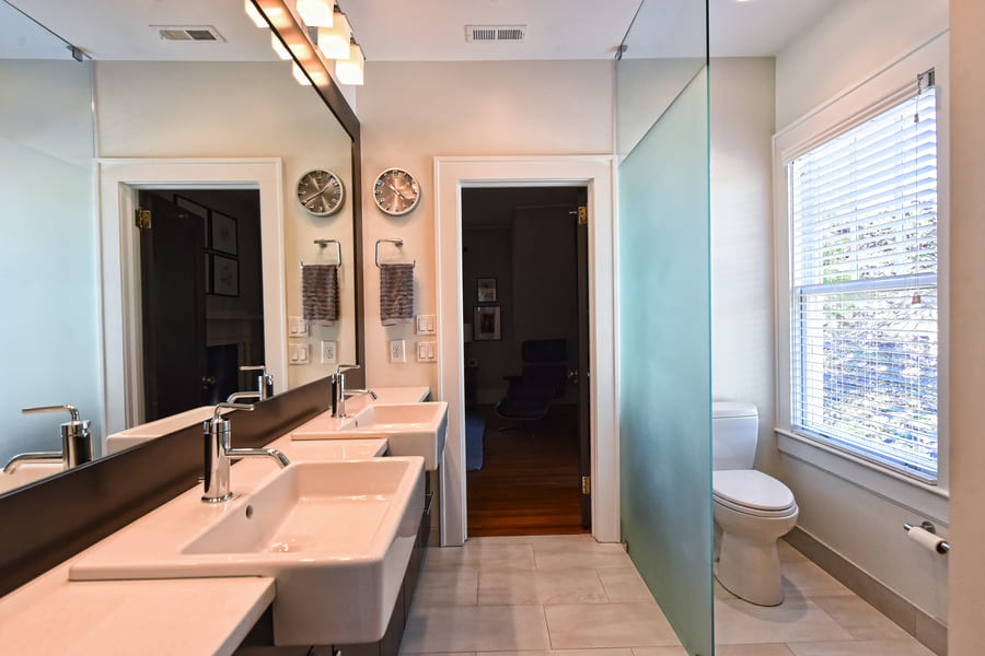 guest bathroom with his and hers white sinks with glass wall blocking toilet by Hopedale Builders in Charlotte NC
