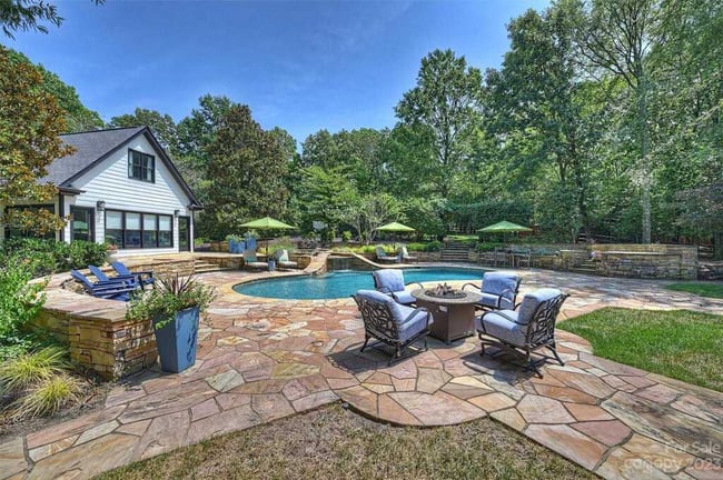 Custom outdoor living featuring a pool, stone patio, and exterior of home by Hopedale Builders in Providence Plantation, North Carolina