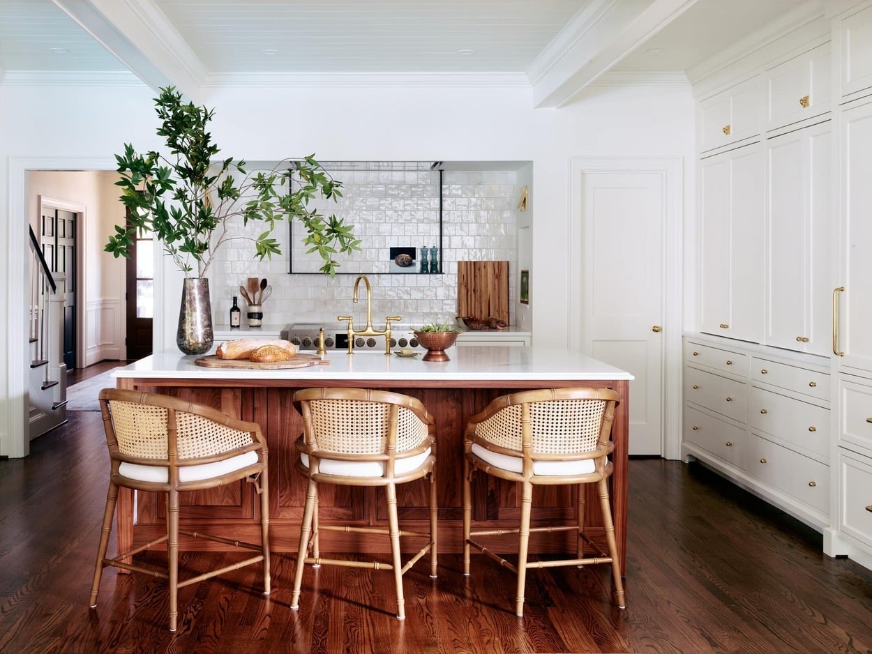 Luxury kitchen remodel in Charlotte, NC with white inset cabinetry, a Fulgor Milano Sofia induction range inside a custom alcove, walnut island featuring Bianco Berrini marble countertops, cane-back counter stools, brass hardware and plumbing fixtures, and glossy white backsplash tile.