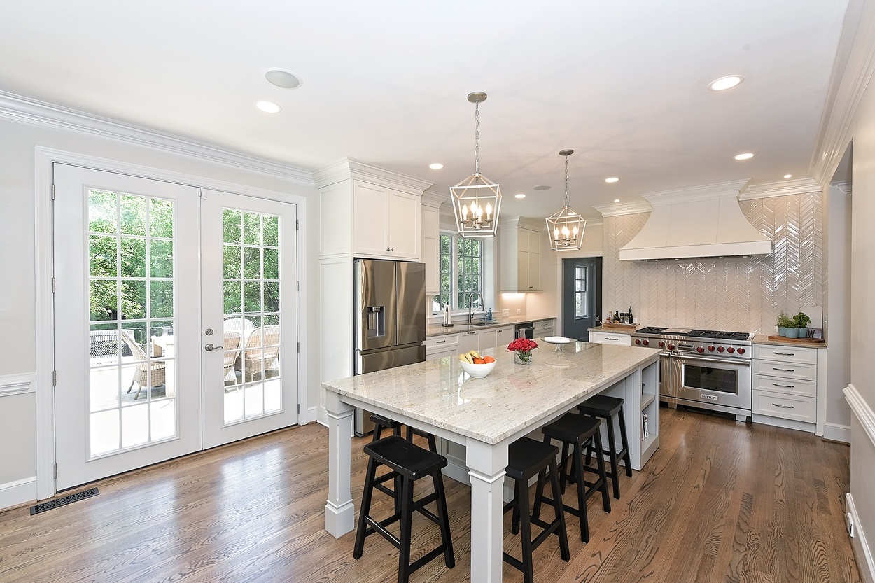 Open-concept kitchen remodel in Raintree, Charlotte, NC by Hopedale Builders with hardwood floors and white cabinetry